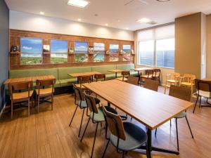 ein Restaurant mit Holztischen, Stühlen und Fenstern in der Unterkunft Comfort Hotel Shin Yamaguchi in Yamaguchi