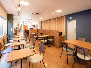Comfort Hotel Shin Yamaguchi في ياماغوتشي: غرفة طعام مع طاولات وكراسي خشبية