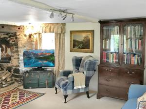 ein Wohnzimmer mit zwei Stühlen und einem Fernseher in der Unterkunft Bratton Mill Farmhouse in Bratton Fleming