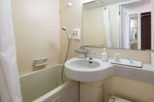 Comfort Hotel Hakodate في هاكوداته: حمام مع حوض وحوض استحمام مع مرآة