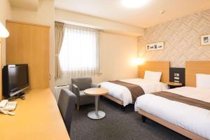 um quarto de hotel com duas camas e uma televisão em Comfort Hotel Kumamoto Shinshigai em Kumamoto