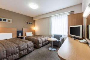 刈谷市にあるコンフォートホテル刈谷のベッド、デスク、テレビが備わるホテルルームです。