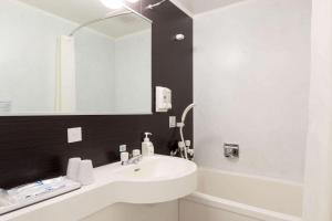 a bathroom with a white sink and a mirror at Comfort Hotel Hachinohe in Hachinohe