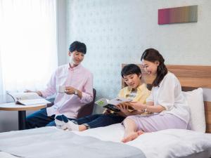 Comfort Hotel Wakayama في واكاياما: مجموعة من ثلاثة أشخاص يجلسون على سرير