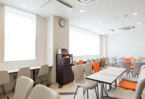 Comfort Hotel Wakayama في واكاياما: غرفة بطاولات وكراسي وساعة على الحائط