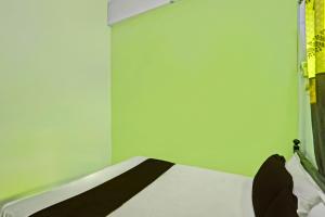 a bed in a room with a green wall at SPOT ON 7 Day Stay in Chandrapur +21 photos