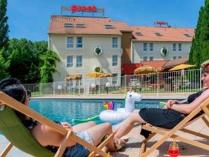 zwei Frauen auf Gartenstühlen neben einem Pool in der Unterkunft greet Hotel Beaune in Beaune