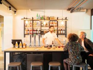 tre persone sedute al bar con un barista di greet Hotel Beaune a Beaune