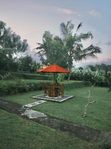 a table and chairs under an umbrella in a field at Papahan Bali in Sidemen