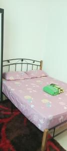 a bed with a pink comforter on top of it at FH Homestay 4BR in Wakaf Baharu