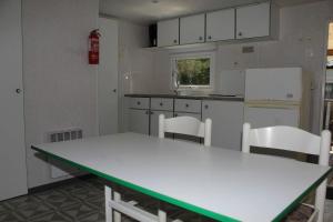 - une cuisine avec une table blanche et des chaises blanches dans l'établissement Mobilhome 3 étoiles - Piscine - eehihe, à Corrèze