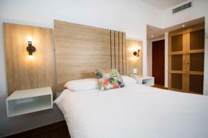パナマシティにあるHotel Faranda Express Soloy and Casino, a member of Radisson Individualsの白いベッド1台(木製ヘッドボード付)が備わるベッドルーム1室が備わります。