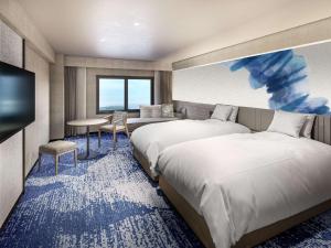ein Hotelzimmer mit 2 Betten und einem TV in der Unterkunft Grand Mercure Wakayama Minabe Resort & Spa in Minabe