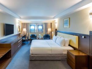 Queen Elizabeth 2 Hotel في دبي: غرفه فندقيه سرير وتلفزيون