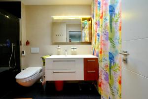 a bathroom with a sink and a toilet and a shower curtain at Room Casa Jessika in Orselina