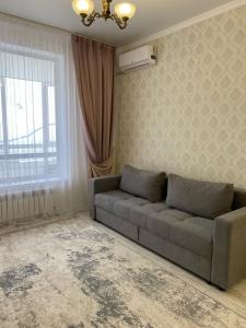 a living room with a couch and a window at INJU апартаменты in Taldykolʼ