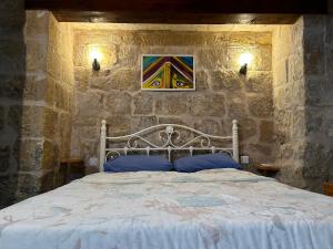 a bedroom with a white bed in a stone wall at Historic Townhouse in Birgu Center in Vittoriosa