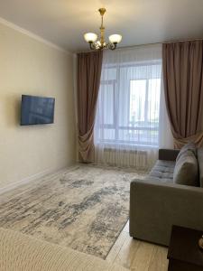 a living room with a couch and a television at INJU апартаменты in Taldykolʼ