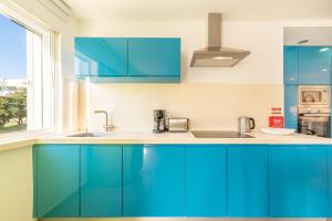 a blue kitchen with a sink and a window at GuestReady - Oasis Retreat in Tróia in Troia