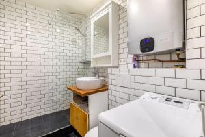 Baño de azulejos blancos con lavabo y aseo en GuestReady - Marvellous escape near Gare du Nord en París