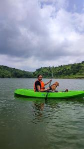 a man and a dog in a kayak on the water at Hiranya Resorts in Daulatābād