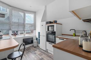 GuestReady - Bright flat in Westminster في لندن: مطبخ به أجهزة بيضاء وطاولة وكراسي