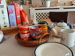 Headington Haven Homestay في أوكسفورد: طاولة عليها سلة مليئة بالطعام وكوب +18 صورة