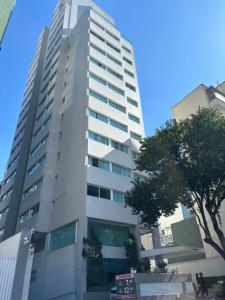 a tall white building with a tree in front of it at Flat 5 min Metrô Paraíso Av Paulista in Sao Paulo