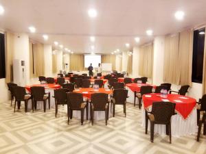 a banquet hall with red tables and chairs and a man at Hiranya Nature Retreat in Daulatābād