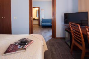 a room with a bed with a tv and a book on a table at Hotel Mariani in Iesi