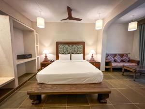 una camera con un grande letto bianco e un divano di Riva Beach Resort a Mandrem
