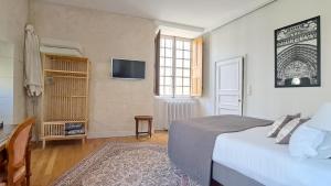- une chambre avec un lit et une télévision murale dans l'établissement LA MAISON CANONIALE luxe et charme au coeur de Tours, à Tours
