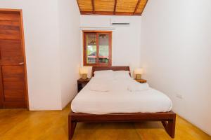 Schlafzimmer mit einem Bett mit weißer Bettwäsche und einem Fenster in der Unterkunft Casa Yosi, Beach Front Piece of Heaven in San Juan del Sur