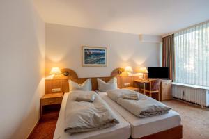 Un dormitorio con una cama grande con dos almohadas. en Aparthotel am Stadtpark, en Bad Sachsa