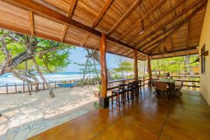 ein Restaurant am Strand mit Tischen und Stühlen in der Unterkunft Casa Yosi, Beach Front Piece of Heaven in San Juan del Sur