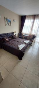 a large bed in a room with chairs and windows at Семеен Хотел ''Кораб Ренеса'' in Ravda +13 photos