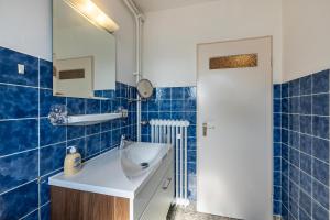 een blauw betegelde badkamer met een wastafel en een spiegel bij Aparthotel am Stadtpark in Bad Sachsa