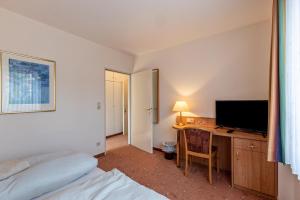 1 dormitorio con escritorio, TV y cama en Aparthotel am Stadtpark, en Bad Sachsa