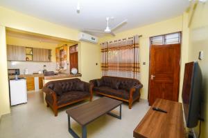 a living room with two couches and a kitchen at MAXIMILIAN HOMES in Kilifi