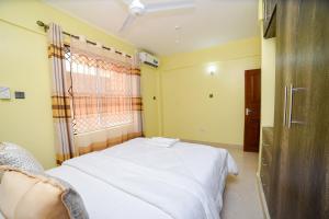 - une chambre avec un lit blanc et une fenêtre dans l'établissement MAXIMILIAN HOMES, à Kilifi