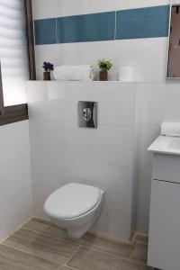 a white bathroom with a toilet and a sink at Domus Bat Galim Hotel in Haifa