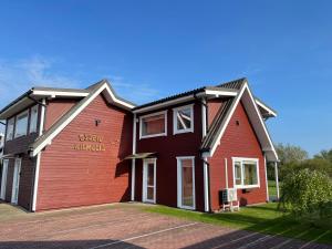 a red and black house with a sign on it at Ošupio kiemelis in Šventoji +15 photos