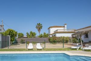 una casa con piscina e due sedie a sdraio di Chalet Villa Ariza a Cadice