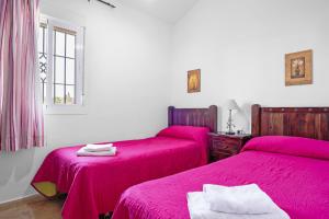 due letti in una stanza con lenzuola rosa di Chalet Villa Ariza a Cadice Altre 19 foto