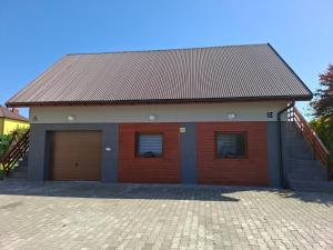a red building with two garage doors and a staircase at Mieszkanie B Łowiczki in Zator