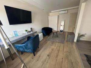 a living room with two blue chairs and a flat screen tv at Brill Hotel Békéscsaba in Békéscsaba