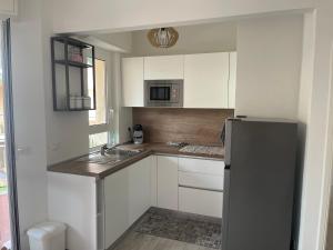 a kitchen with white cabinets and a stainless steel refrigerator at Casa Viki in Pietra Ligure