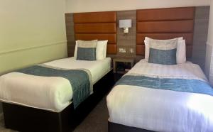 Bushtown Hotel & Spa في كوليرين: سريرين في غرفة الفندق مع تنورات
