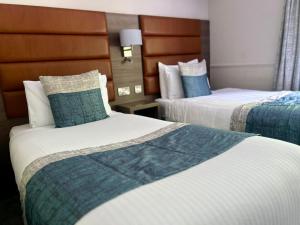 um quarto de hotel com duas camas em azul e branco em Bushtown Hotel & Spa em Coleraine