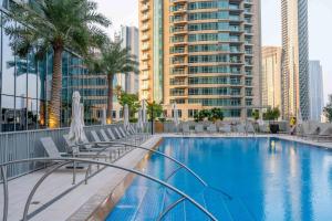 a swimming pool with chairs and palm trees in a city at GuestReady - Glamourous home in Downtown Dubai in Dubai